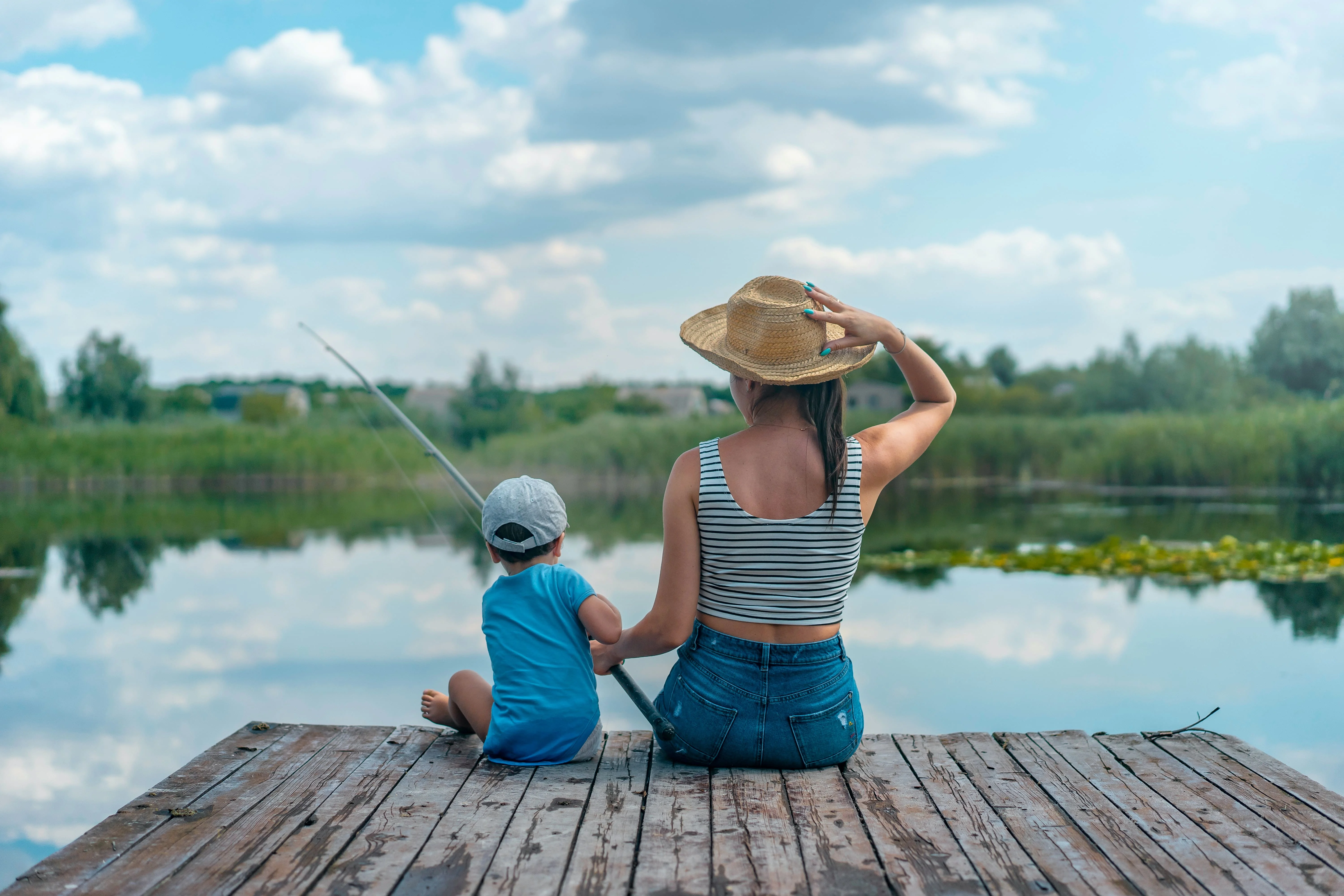 A mother is fishing with her kid to teach him patience a virtue meaning the essence of strong well-being.